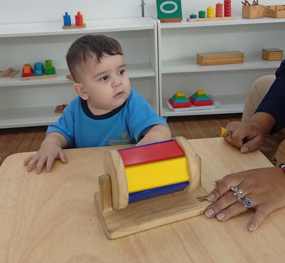 Bébé paisible explorant un matériel dans l'ambiance, les étagères en arrière-plan