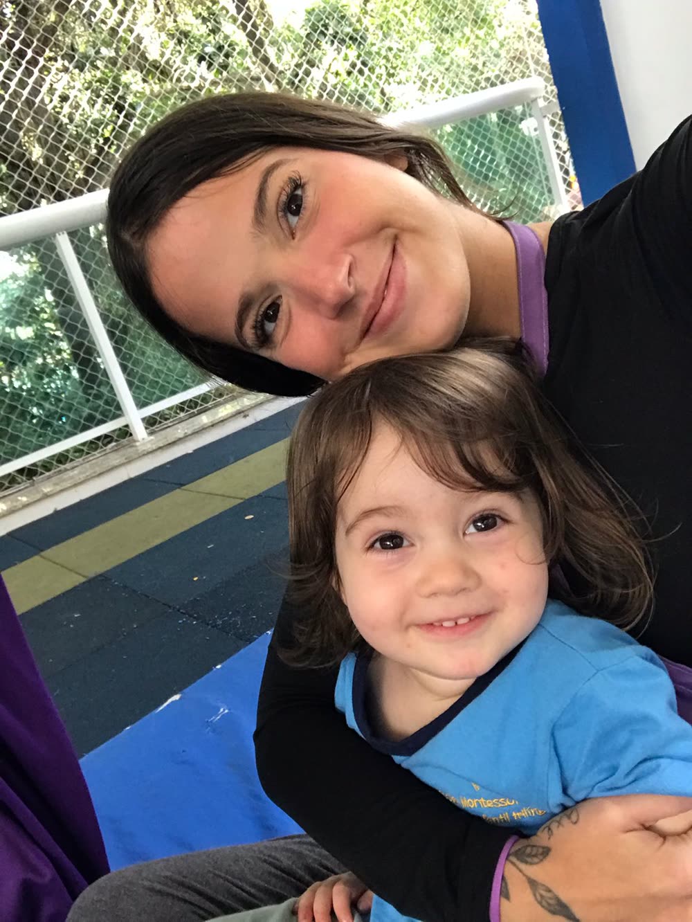 Professora sorrindo acolhe criança pequena na sala durante a adaptação