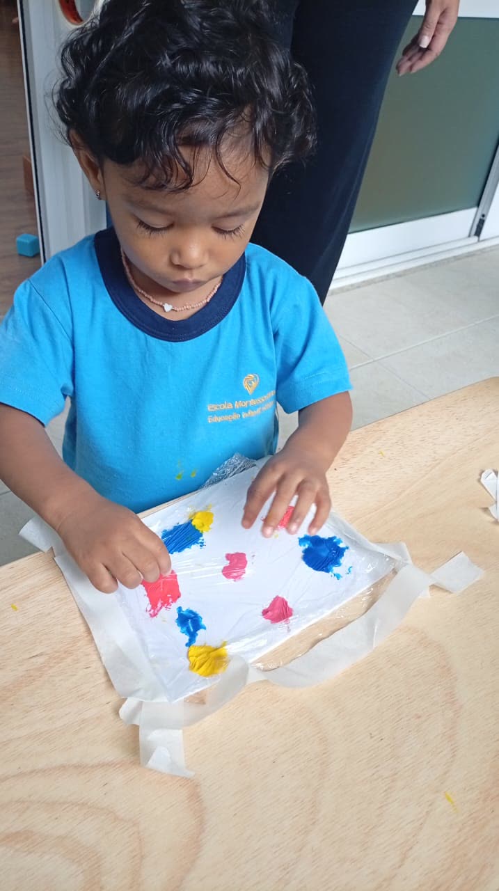 Bebê pintando com as mãos usando as cores primárias sobre o papel