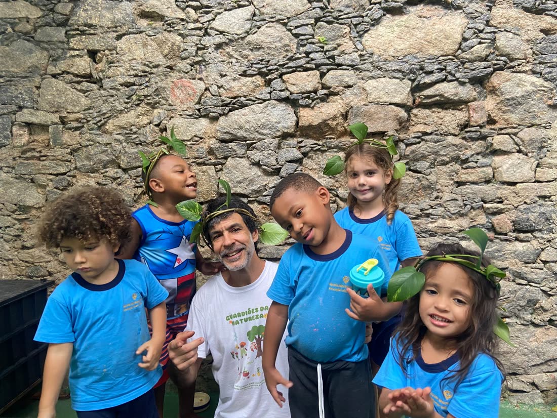 Grupo de crianças com coroas de folhas na área verde da escola