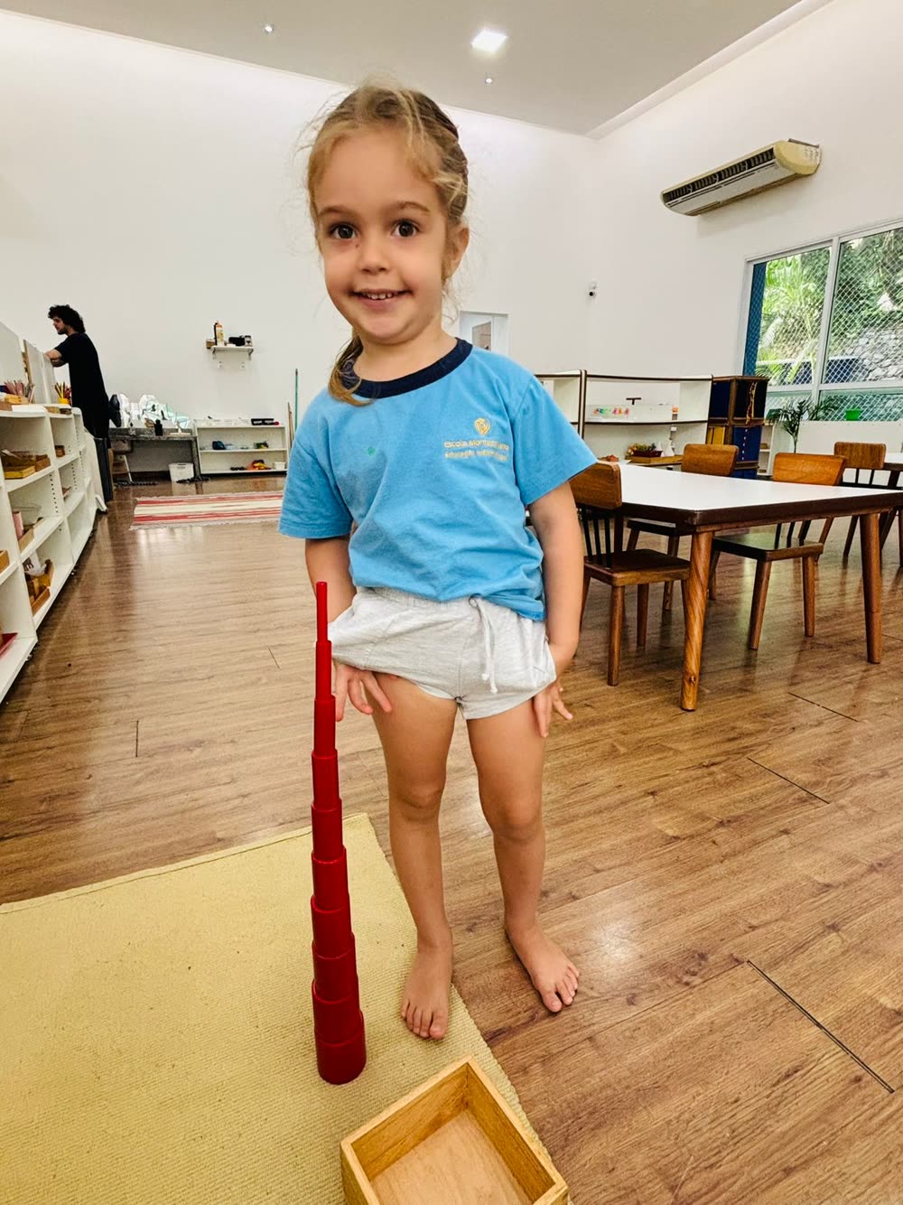 Menina concentrada montando a torre rosa na sala Montessori